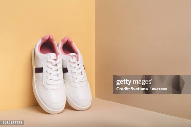 white sport sneakers shoes on the beige background. - pair stock photos et images de collection