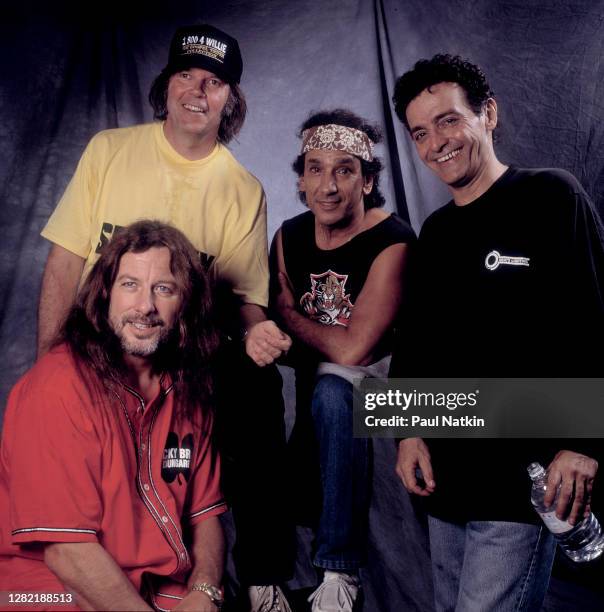 Canadian Folk and Rock musician Neil Young and members of the band Crazy Horse pose together backstage during the Farm Aid benefit concert at the New...