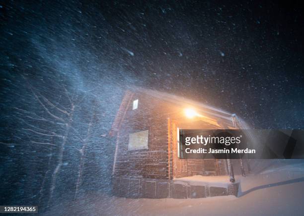 wood cabin in winter blizzard snowstorm at night - cabin in the woods stock-fotos und bilder