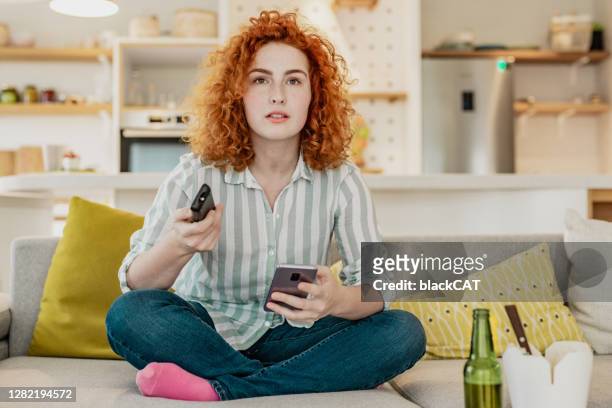 la giovane donna preoccupata sta guardando la tv - serio foto e immagini stock