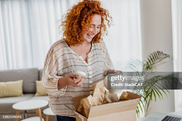 junge frau packt das paket aus, das sie online bestellt hat - online shopping opening package stock-fotos und bilder