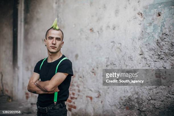 male punk person standing by the wall in abandoned building - traditional piercings stock pictures, royalty-free photos & images