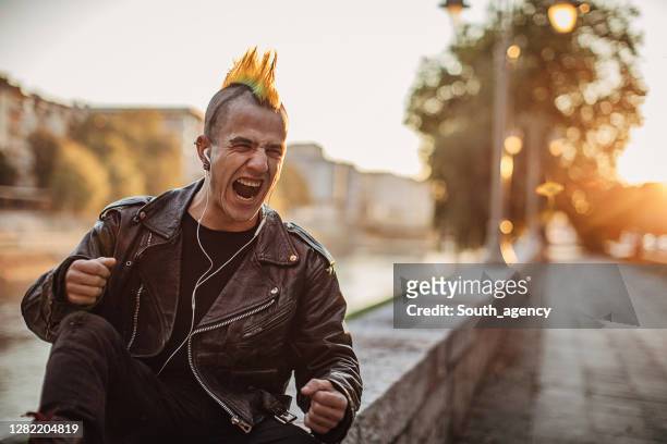 punker listening music on headphones and shouting on the street - mohawk stock pictures, royalty-free photos & images