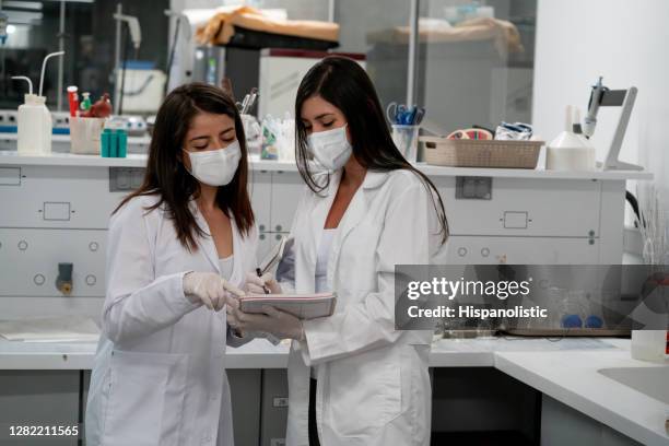 team of female students doing research at the lab wearing protective gloves and face mask - biosecurity stock pictures, royalty-free photos & images