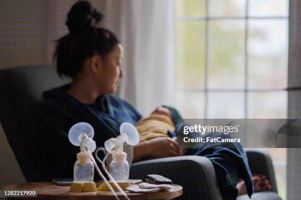 vermoeide nieuwe moeder die haar baby houdt - relatieproblemen stockfoto's en -beelden