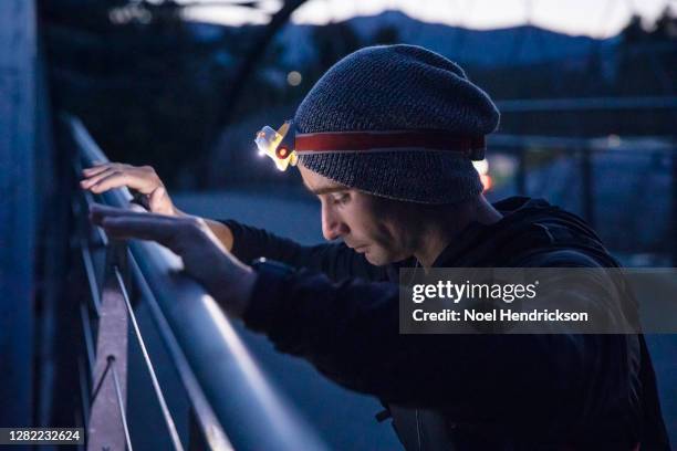 male runner taking a breather on the railing - head torch stock pictures, royalty-free photos & images