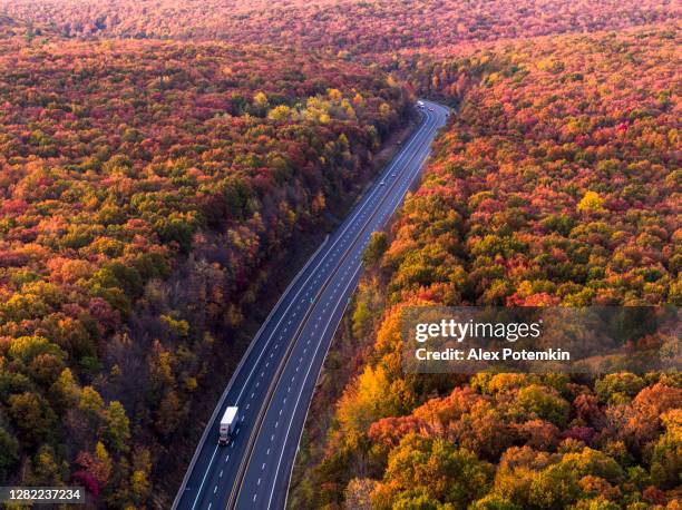 lkw fahren eine autobahn in den bergen in den frühen morgenstunden, direkt nach sonnenuntergang, in der bunten herbstsaison. - pocono stock-fotos und bilder