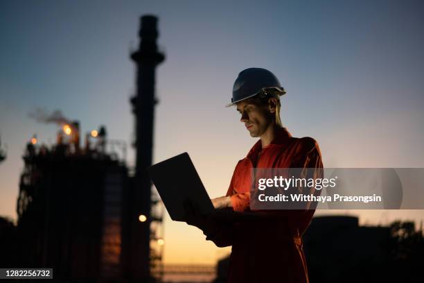 asian man engineer using digital tablet working late night shift at petroleum oil refinery - oil workers ストックフォトと画像