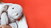 Toy grey rabbit on orange background. plaything