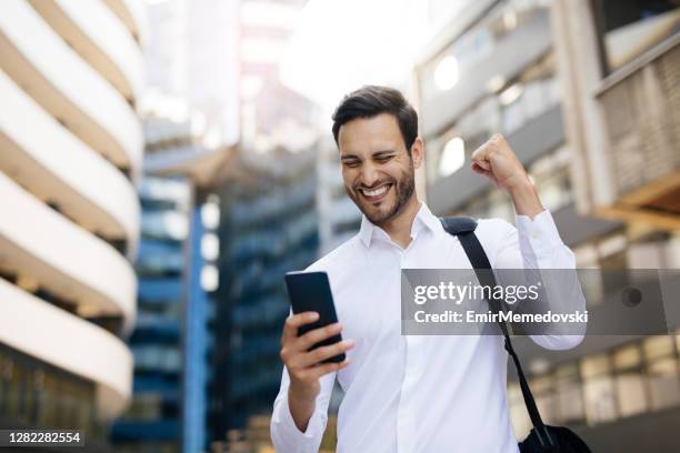 recibir una buena noticia por teléfono - fist celebrating fotografías e imágenes de stock