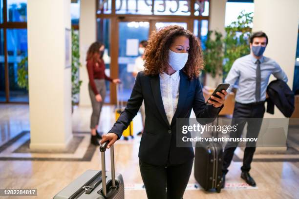 hotel guests wearing protective face mask and keeping social distance during covid-19 - hotel reopening stock pictures, royalty-free photos & images