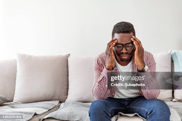 african-american man suffering from headache at home - man headache stock pictures, royalty-free photos & images