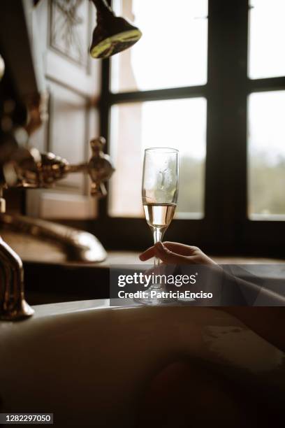 young woman drinking champagne in a bathtub - bubble bath bottle stock pictures, royalty-free photos & images