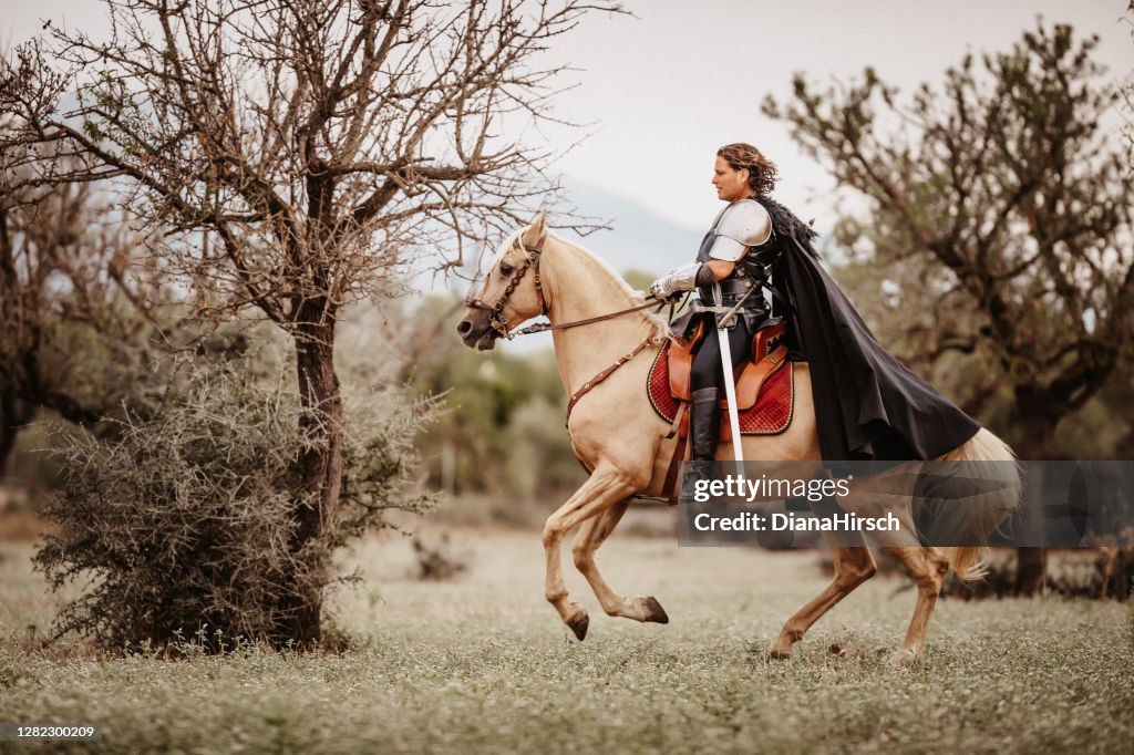 Caballero de fantasía medieval montando en su caballo palomino de derecha a izquierda