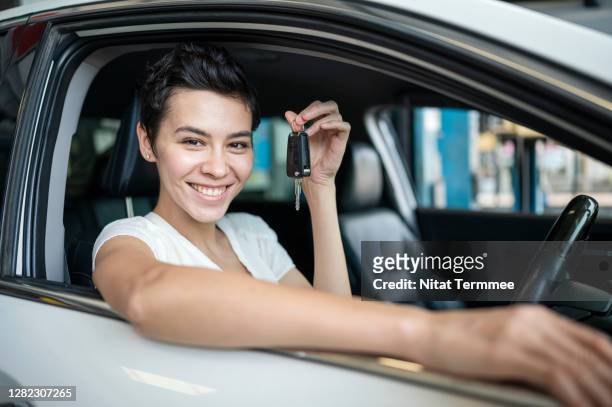 a happy women customer holding a car key in the auto repair shop testing car after repairing complete. - test drive stock pictures, royalty-free photos & images