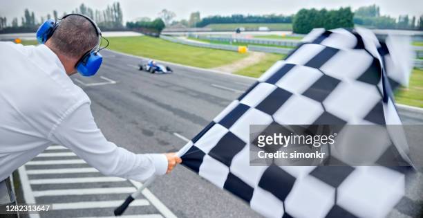 auto-rennen offiziell winken karierte flagge - car racing stock-fotos und bilder