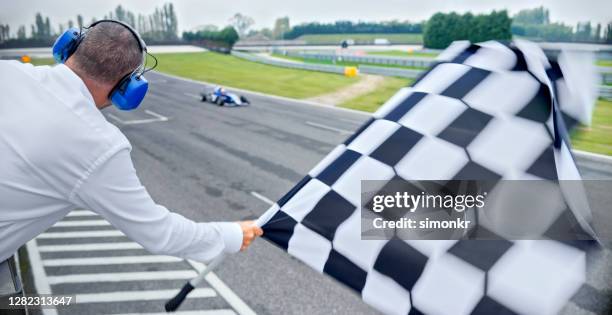 drapeau à damier de course d’auto agitant - voiture de course photos et images de collection