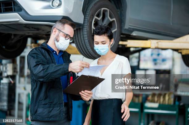 a customer service explaining fixing detail of car to female client at an auto repair center. customer service, quality of service. - customer experience stock pictures, royalty-free photos & images