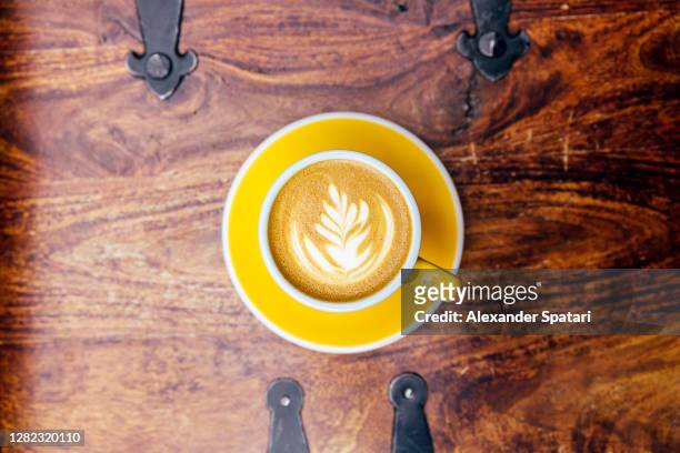 yellow cup of coffee with latte art, directly above view - yellow milk stock-fotos und bilder