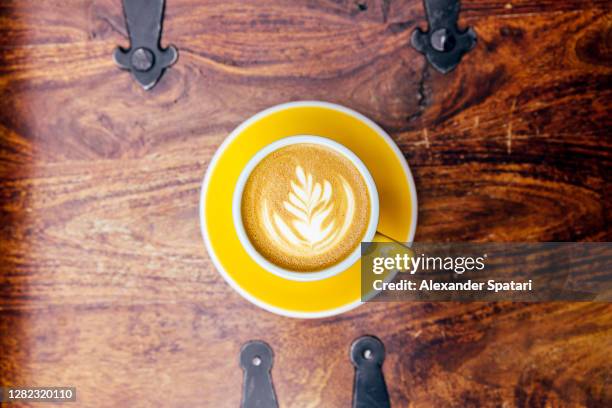 yellow cup of coffee with latte art, directly above view - latte stock pictures, royalty-free photos & images