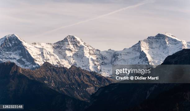 stunning panorama of the famous eiger, mönch and jungfrau peaks in the swiss alps - berg mönch stock-fotos und bilder