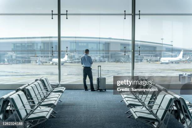 businessman waiting to board in airport terminal - vestíbulo edificio de transporte fotografías e imágenes de stock