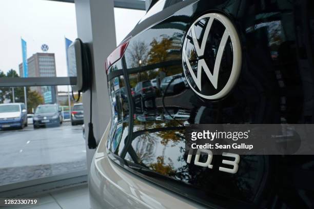 Volkswagen ID.3 electric car stands on display at a car dealership as the Volkswagen corporate headquarters building is seen through the window on...