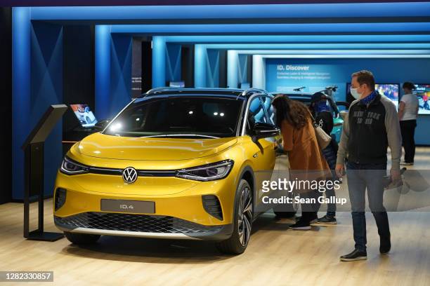 Visitors look at an Volkswagen ID.4 electric car at the Autostadt promotional facility next to the Volkswagen factory on October 26, 2020 in...