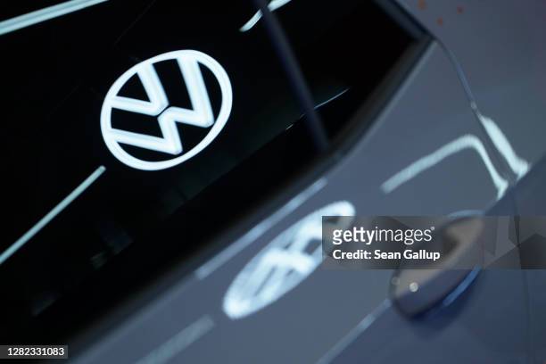 The Volkswagen logo is reflected in the window and body of a Volkswagen ID.3 electric car standingt on display at the Autostadt promotional facility...