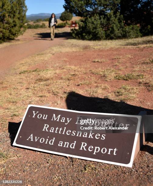 Tourist approaches a sign in Pecos National Historical Park warning of the presence of rattlesnakes in the park managed by the National Park Service....