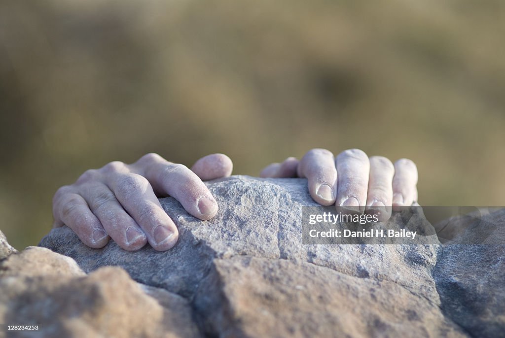 Climbers hands grabbing the top of a rock ledge