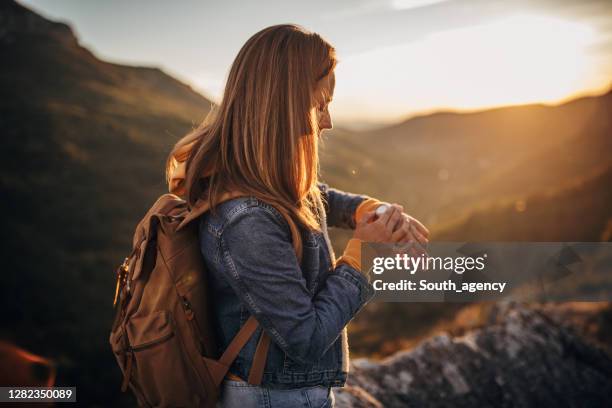 one young woman hiker checking the time on wristwatch - climbs to all time high stock pictures, royalty-free photos & images