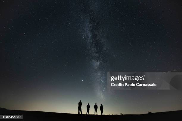 four people in silhouette under milky way - stars group stock pictures, royalty-free photos & images
