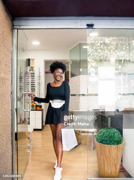 young customer choosing eyeglasses in store - leaving store stock pictures, royalty-free photos & images