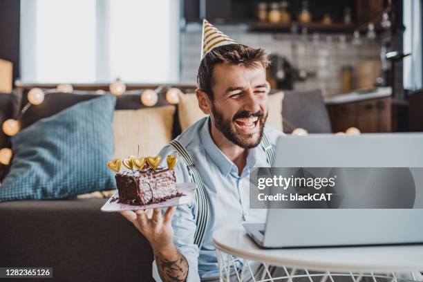 young man celebrating birthday on a video call at home - zoom birthday stock pictures, royalty-free photos & images