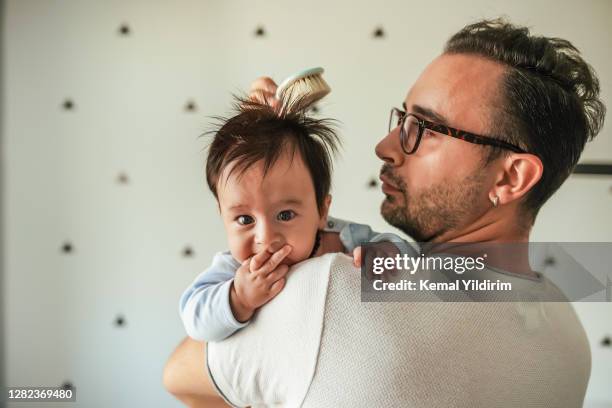 modern dad brushing his baby boys hair with natural newborn brush - suck stock pictures, royalty-free photos & images