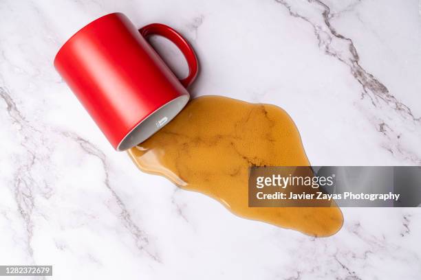 coffee spilling out from a coffee cup on a marble surface - café rouge photos et images de collection