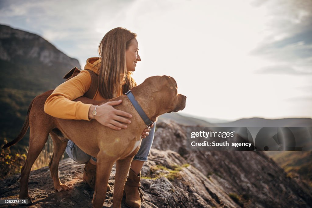 Escursionista donna con il suo cane sulla vetta della montagna