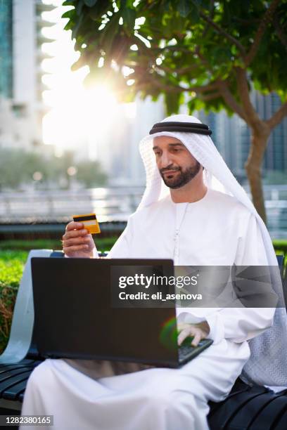 arabischer geschäftsmann arbeitet mit laptop im freien in dubai marina - emirati guy using laptop stock-fotos und bilder