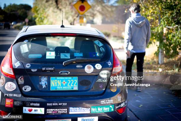 santa fe, nm:  pedestrian walks past car with bumper stickers - ford fiesta cars stock pictures, royalty-free photos & images
