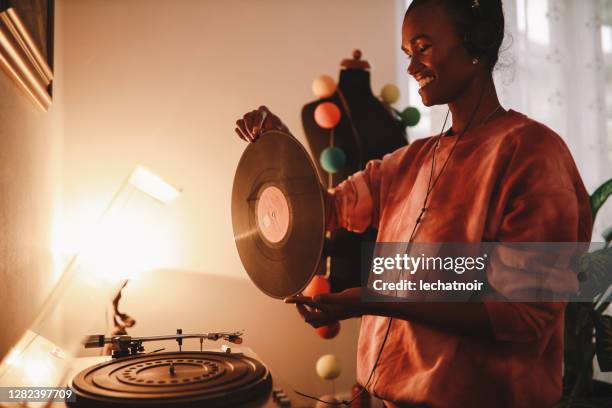 joven mujer con camisa de tinte de corbata jugando su colección de discos en casa - record player fotografías e imágenes de stock