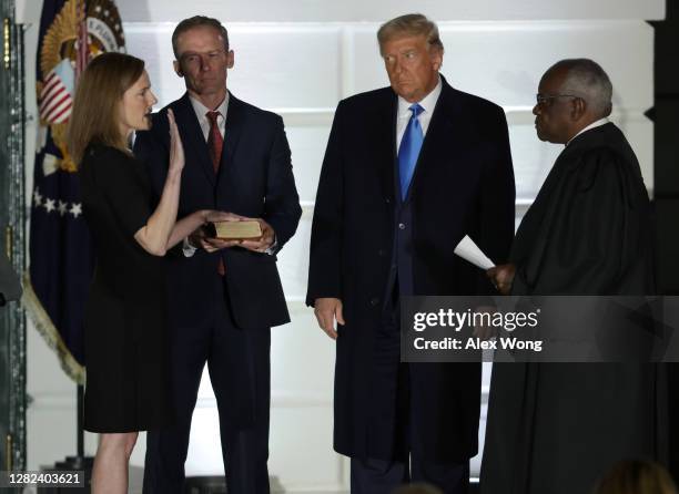 President Donald Trump watches as U.S. Supreme Court Associate Justice Amy Coney Barrett is sworn in by Supreme Court Associate Justice Clarence...