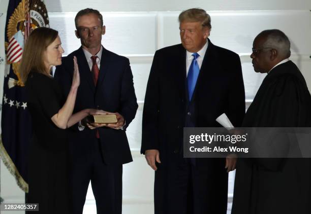 President Donald Trump watches as U.S. Supreme Court Associate Justice Amy Coney Barrett is sworn in by Supreme Court Associate Justice Clarence...