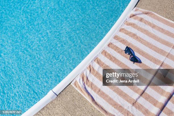 summer background: striped beach towel with cateye sunglasses next to swimming pool - striped towel stock pictures, royalty-free photos & images