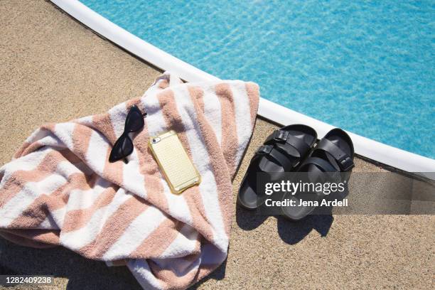 summer accessories: cateye sunglasses, cell phone, beach towel and sandals next to pool - striped towel stock pictures, royalty-free photos & images
