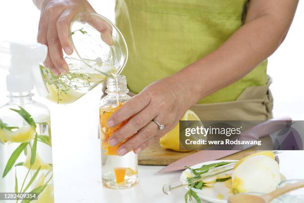 woman do infusing vinegar combines with orange peel into spray bottle, natural homemade cleaner - dragon stockfoto's en -beelden