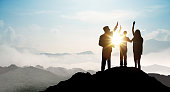 Silhouette of Business team show arm up on top of the mountain. Leadership and success Concept.