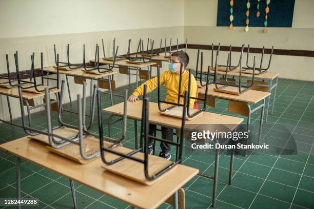 one boy only sitting alone in empty classrom - last day of school stock pictures, royalty-free photos & images