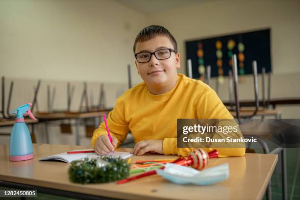 school boy at the desk in an empty clasroom - last day of school stock pictures, royalty-free photos & images