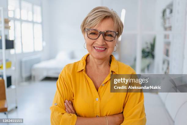 porträt einer lächelnden seniorin in ihrem wohnzimmer - grey hair cool woman stock-fotos und bilder